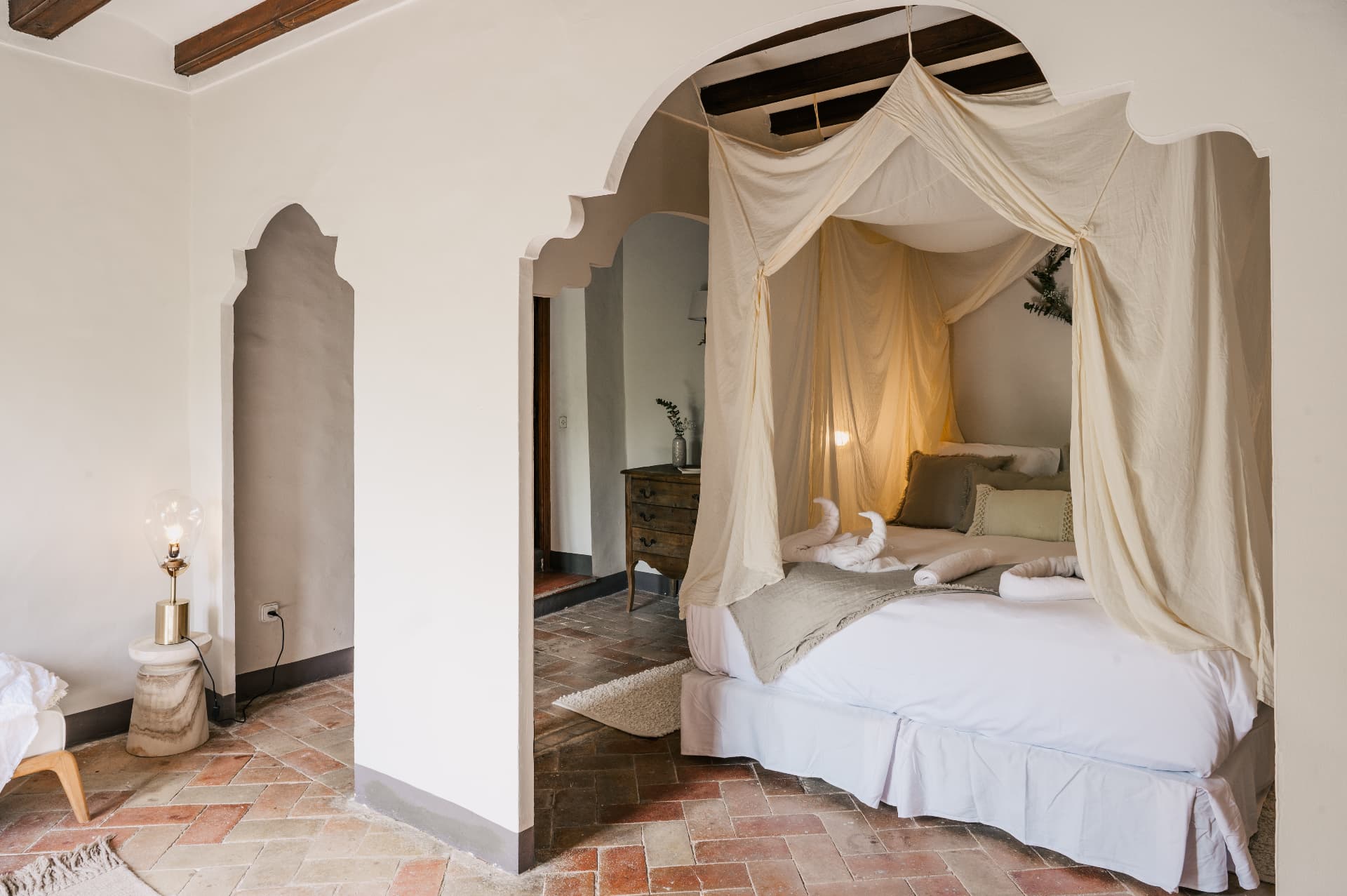 Canopy bed framed by a carved plaster arch