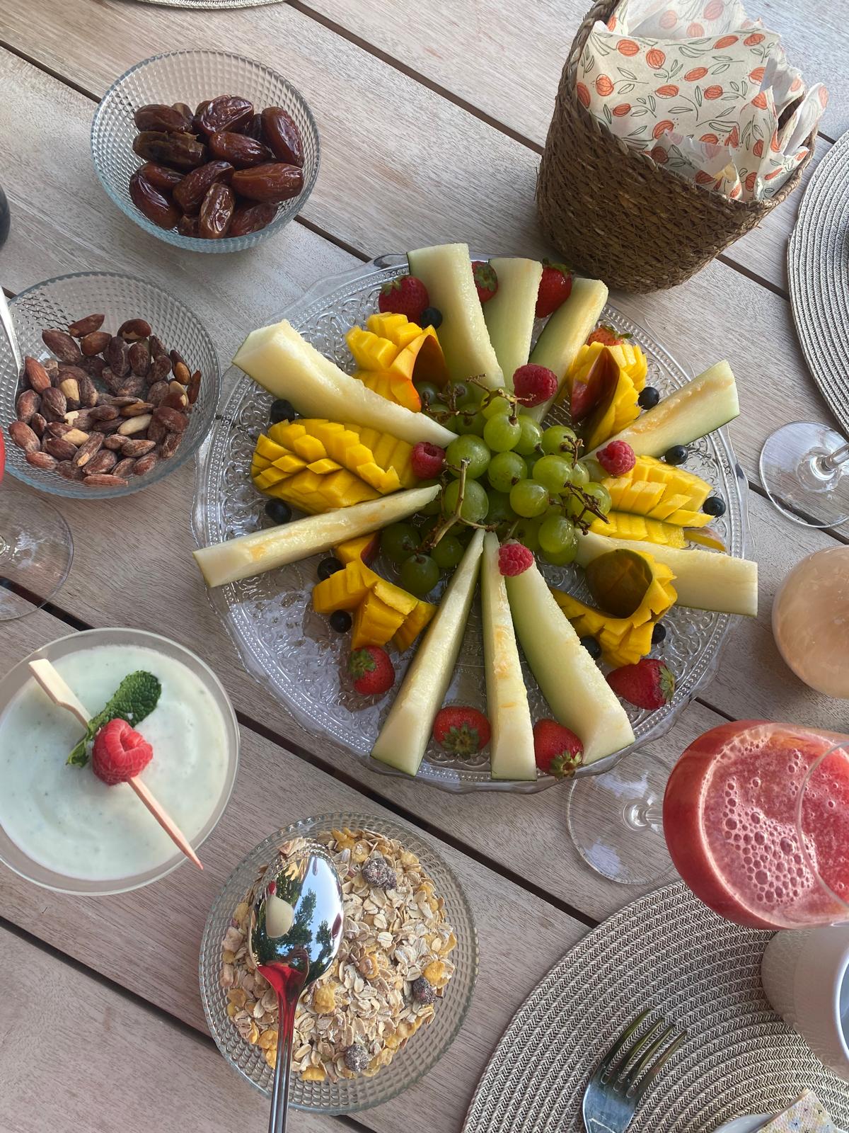 Fresh fruit platter with dates, nuts and smoothies on a terrace table